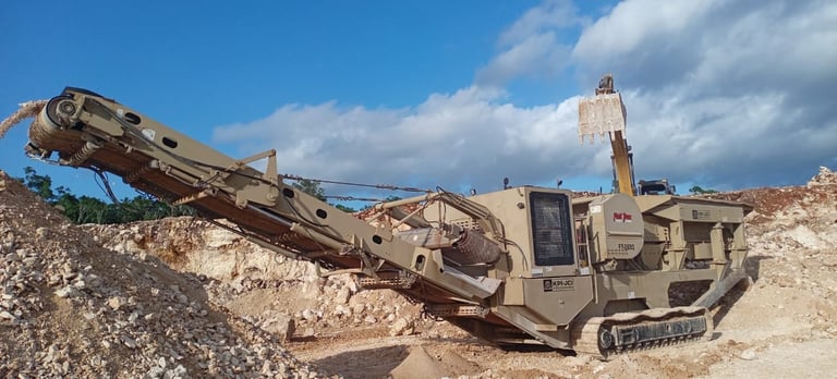 Tan mobile jaw crusher processing rocky debris on construction site under blue sky