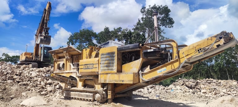 Yellow industrial mobile jaw crusher processing crushed stone and rock debris at a construction site